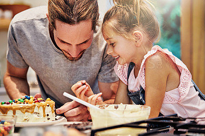 Buy stock photo Shot of a handsome young man baking a cake with his daughter
