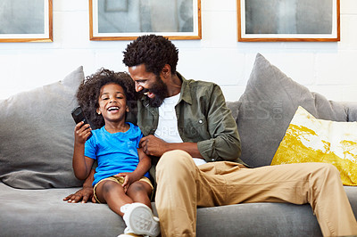 Buy stock photo Shot of a cheerful young father and son relaxing on a couch while watching television at home