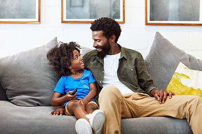 Buy stock photo Shot of a cheerful young father and son relaxing on a couch while watching television at home