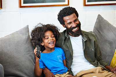 Buy stock photo Shot of a cheerful young father and son relaxing on a couch while watching television at home