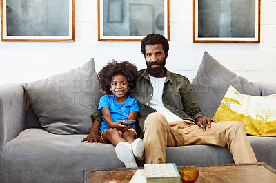 Buy stock photo Portrait of a cheerful young father and son relaxing on a couch while watching television at home