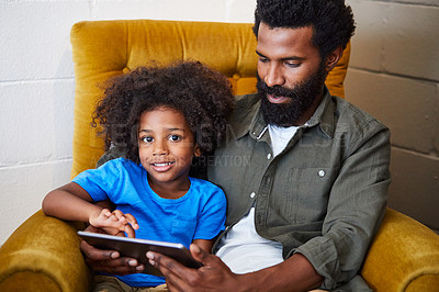 Buy stock photo Portrait of a cheerful young father and son relaxing on a chair while browsing on a digital tablet at home