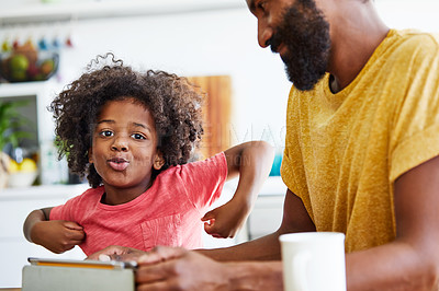 Buy stock photo Portrait of a cheerful young father and son browsing on a digital tablet while having a cup of coffee in the kitchen at home
