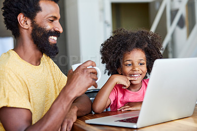 Buy stock photo Shot of a cheerful young father and son browsing on a digital tablet together while being seated at a table in their home