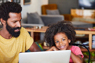 Buy stock photo Portrait of a cheerful young father and son browsing on a digital tablet together while being seated at a table in their home