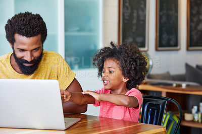 Buy stock photo Shot of a cheerful young father and son browsing on a digital tablet together while being seated at a table in their home