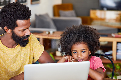 Buy stock photo Shot of a cheerful young father and son browsing on a digital tablet together while being seated at a table in their home