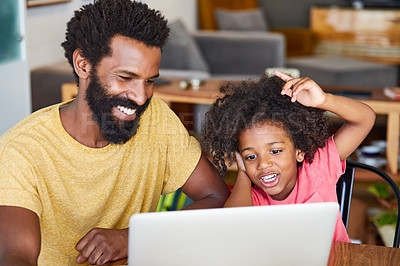 Buy stock photo Shot of a cheerful young father and son browsing on a digital tablet together while being seated at a table in their home