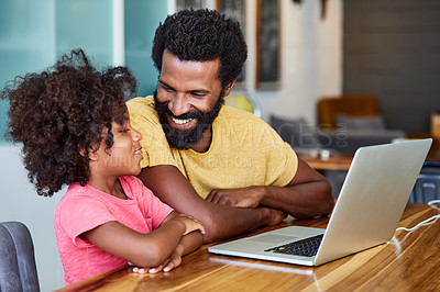Buy stock photo Shot of a cheerful young father and son browsing on a digital tablet together while being seated at a table in their home