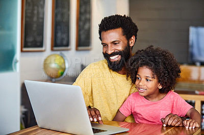 Buy stock photo Shot of a cheerful young father and son browsing on a digital tablet together while being seated at a table in their home