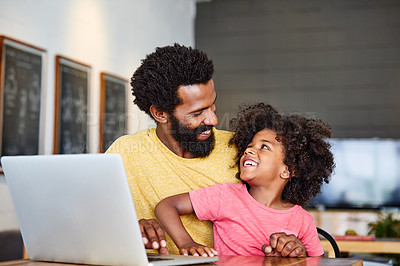 Buy stock photo Shot of a cheerful young father and son browsing on a digital tablet together while being seated at a table in their home