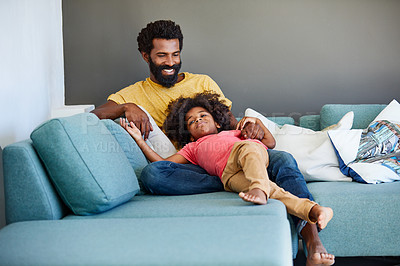 Buy stock photo Shot of a cheerful young father and son relaxing on a couch at home during the day