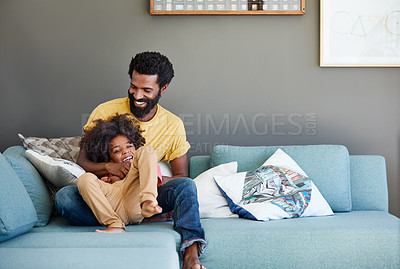 Buy stock photo Shot of a cheerful young father and son relaxing on a couch at home during the day