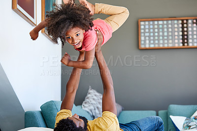 Buy stock photo Shot of a cheerful little boy getting picked up by his dad while lying down on the floor