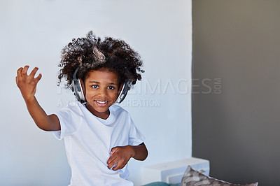 Buy stock photo Portrait of a cheerful young little boy dancing on a couch while listening to music at home during the day