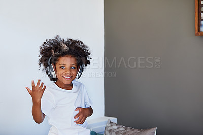 Buy stock photo Portrait of a cheerful young little boy dancing on a couch while listening to music at home during the day