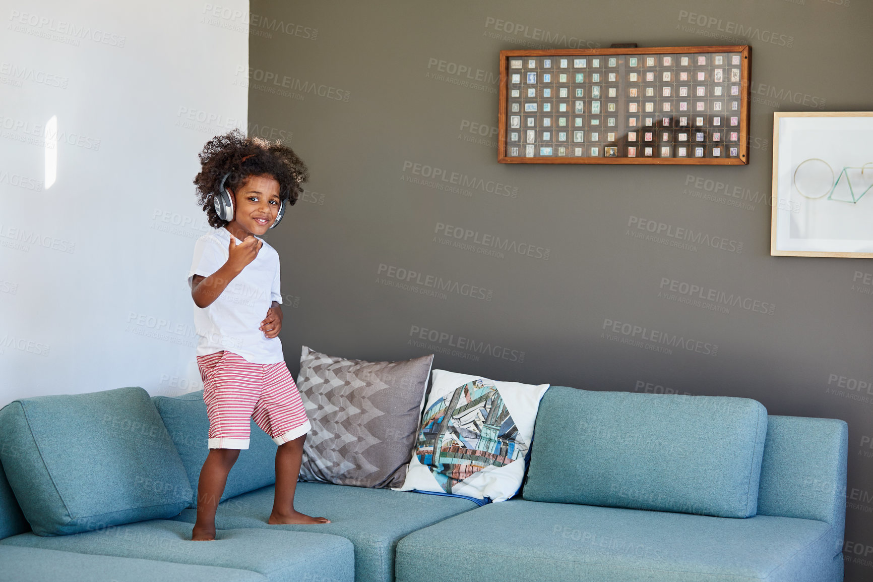 Buy stock photo Portrait, child and dance in home with headphones, pretend musician and music for imaginary concert. Smile, kid and playing on sofa with air guitar, rock star fantasy and song for musical performance