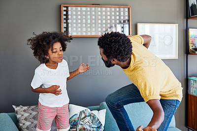 Buy stock photo Shot of a cheerful young father and his son dancing on a couch while listening to music at home during the day