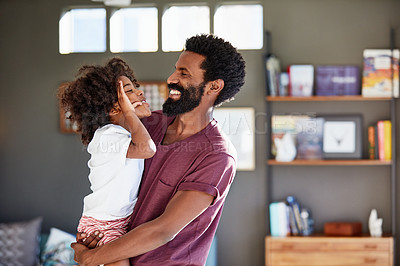 Buy stock photo Shot of a cheerful young father holding his son while looking at each other inside at home during the day
