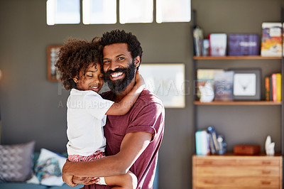 Buy stock photo Portrait of a cheerful young father holding his son while looking at the camera inside at home during the day