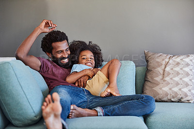 Buy stock photo Shot of a cheerful father and son lying down and relaxing on the couch at home during the day
