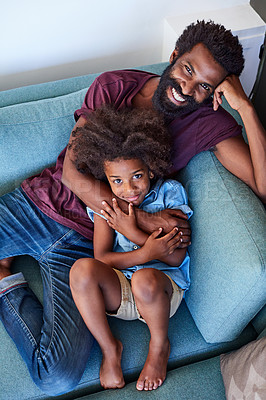 Buy stock photo High angle shot of a cheerful father and son lying down and relaxing on the couch at home during the day