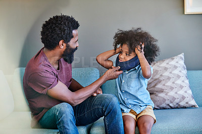 Buy stock photo Shot of a cheerful father and son seated on a couch while playing around in the living room at home