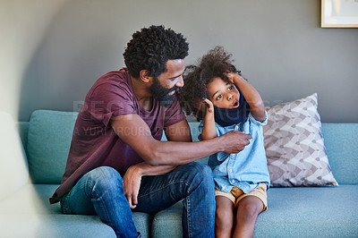Buy stock photo Shot of a cheerful father and son seated on a couch while playing around in the living room at home