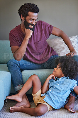 Buy stock photo Shot of a cheerful father and son striking a pose while being seated on the couch at home during the day