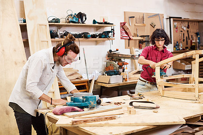 Buy stock photo Shot of two people working with wood in a furniture manufacturing workshop