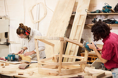 Buy stock photo Shot of two people working with wood in a furniture manufacturing workshop