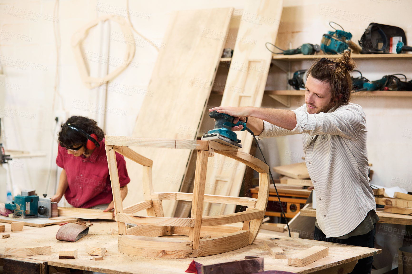 Buy stock photo Shot of two people working with wood in a furniture manufacturing workshop