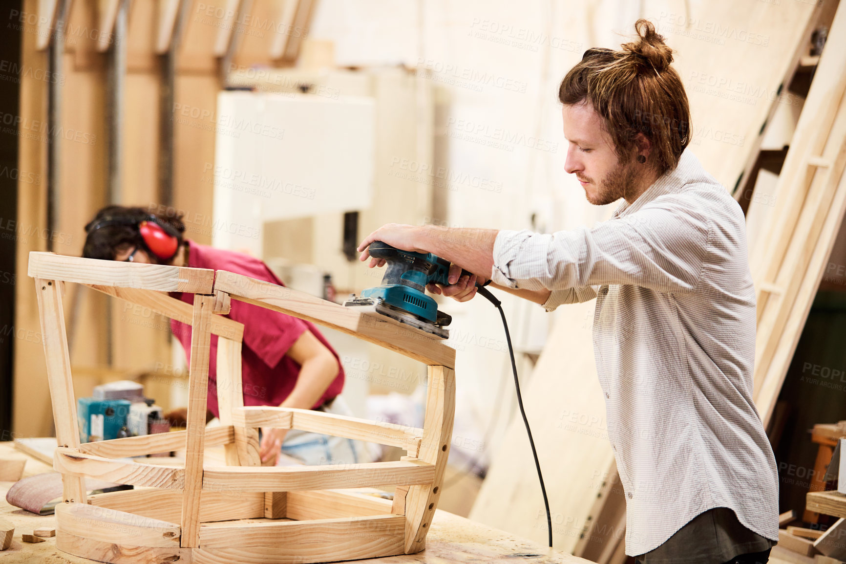 Buy stock photo Shot of two people working with wood in a furniture manufacturing workshop
