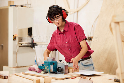 Buy stock photo Shot of a woman working with wood in a furniture manufacturing workshop