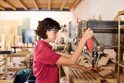 Buy stock photo Shot of a woman working with wood in a furniture manufacturing workshop