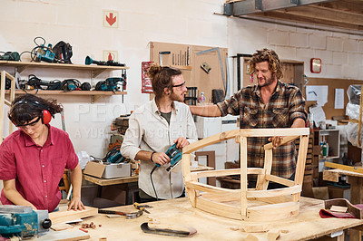 Buy stock photo Shot of three people working with wood in a furniture manufacturing workshop