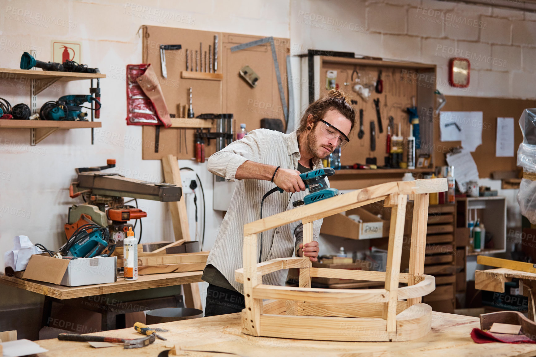 Buy stock photo Woodworking, safety glasses and man with sander in workshop, furniture design and smooth with tool. Creative, carpenter and person with power equipment, polish and craftsmanship project in woodshop