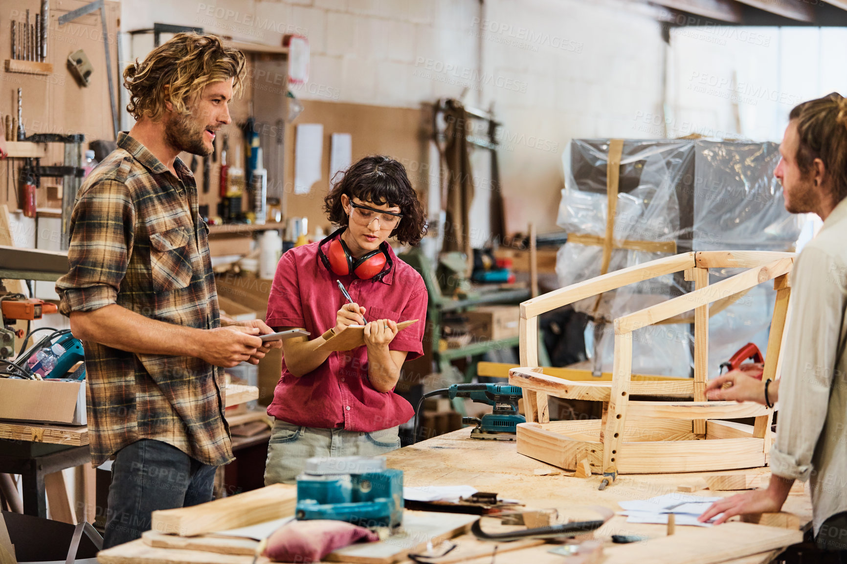 Buy stock photo Shot of three people working with wood in a furniture manufacturing workshop