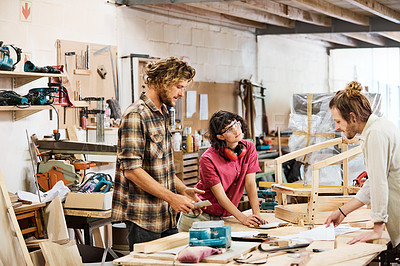 Buy stock photo Shot of three people working with wood in a furniture manufacturing workshop
