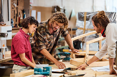 Buy stock photo Shot of three people working with wood in a furniture manufacturing workshop
