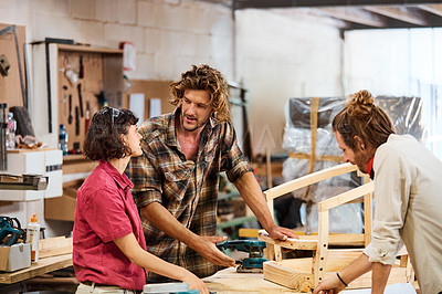 Buy stock photo Shot of three people working with wood in a furniture manufacturing workshop