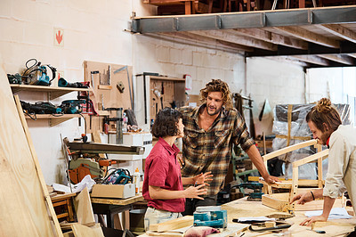 Buy stock photo Shot of three people working with wood in a furniture manufacturing workshop