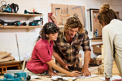 Buy stock photo Shot of three people working with wood in a furniture manufacturing workshop