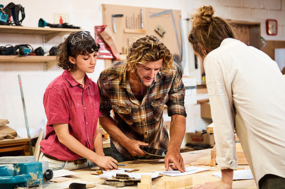 Buy stock photo Shot of three people working with wood in a furniture manufacturing workshop