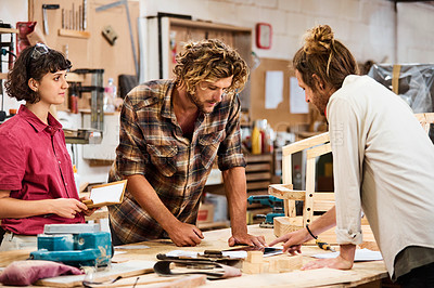 Buy stock photo Shot of three people working with wood in a furniture manufacturing workshop