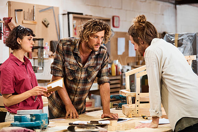 Buy stock photo Shot of three people working with wood in a furniture manufacturing workshop