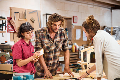 Buy stock photo Shot of three people working with wood in a furniture manufacturing workshop