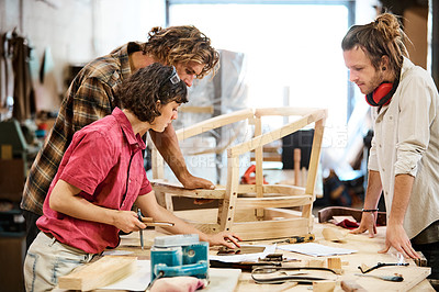 Buy stock photo Shot of three people working with wood in a furniture manufacturing workshop
