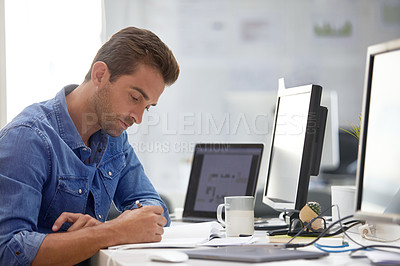 Buy stock photo Cropped shot of a businessman making notes at his desk