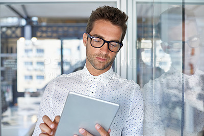 Buy stock photo Cropped shot of a handsome businessman using his digital tablet at work